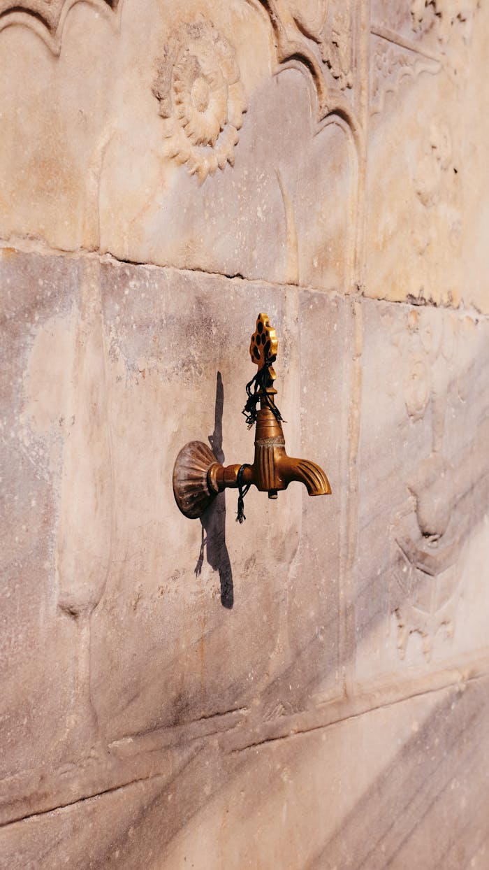 Close-up of a vintage brass faucet on a stone wall in Istanbul, Türkiye.